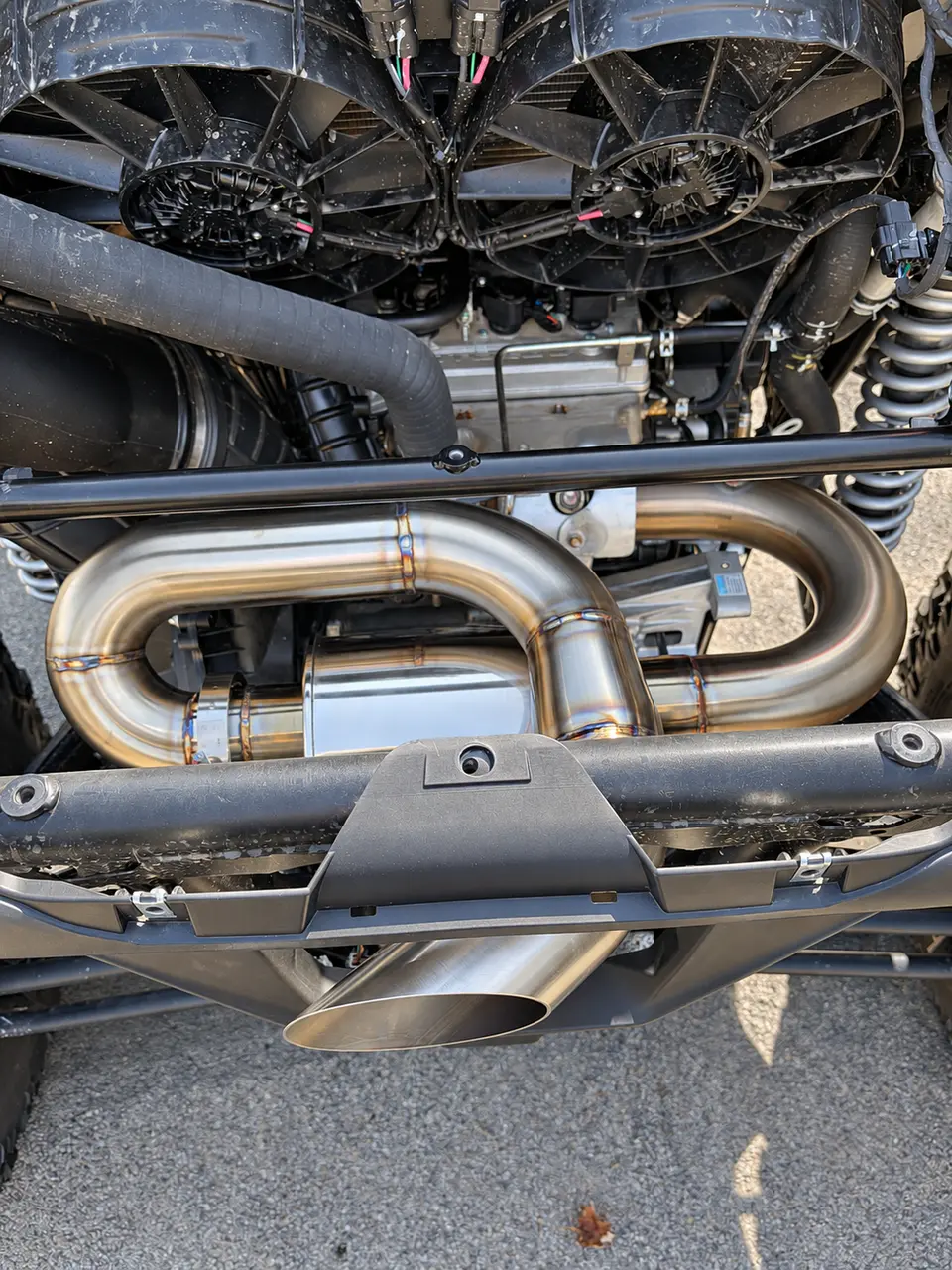 The signature RECOIL look. Sweeping looped piping, exposed weld detail, and an angle-cut outlet take center stage in this close-up behind the rear bumper.